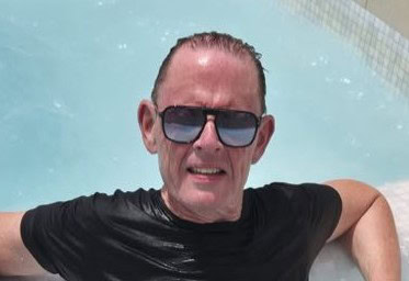 - Visage souriant d'un homme d'age moyen avec des lunettes de soleil, dans une piscine