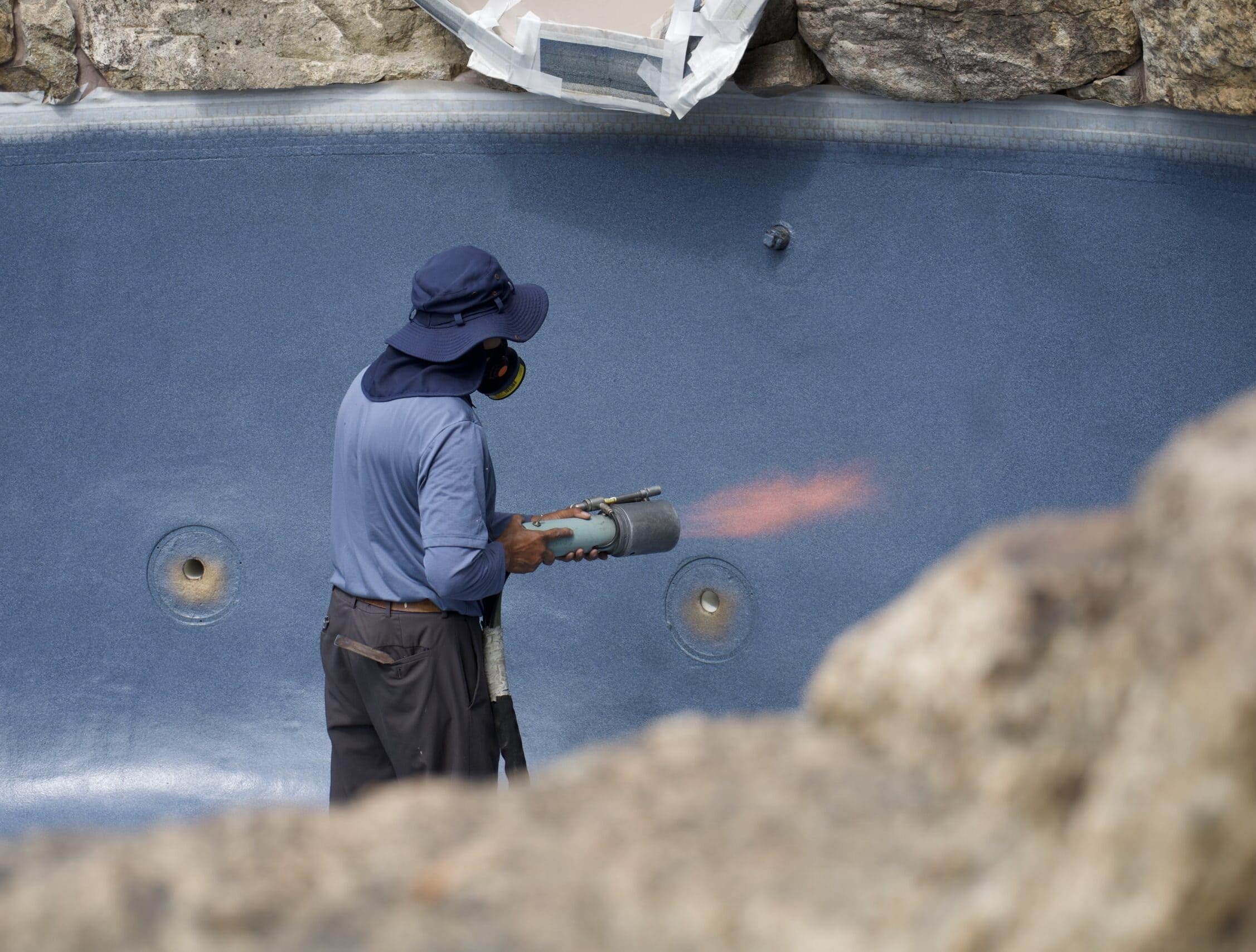 Technicien installant un liner de piscine avec un pistolet à air chaud.