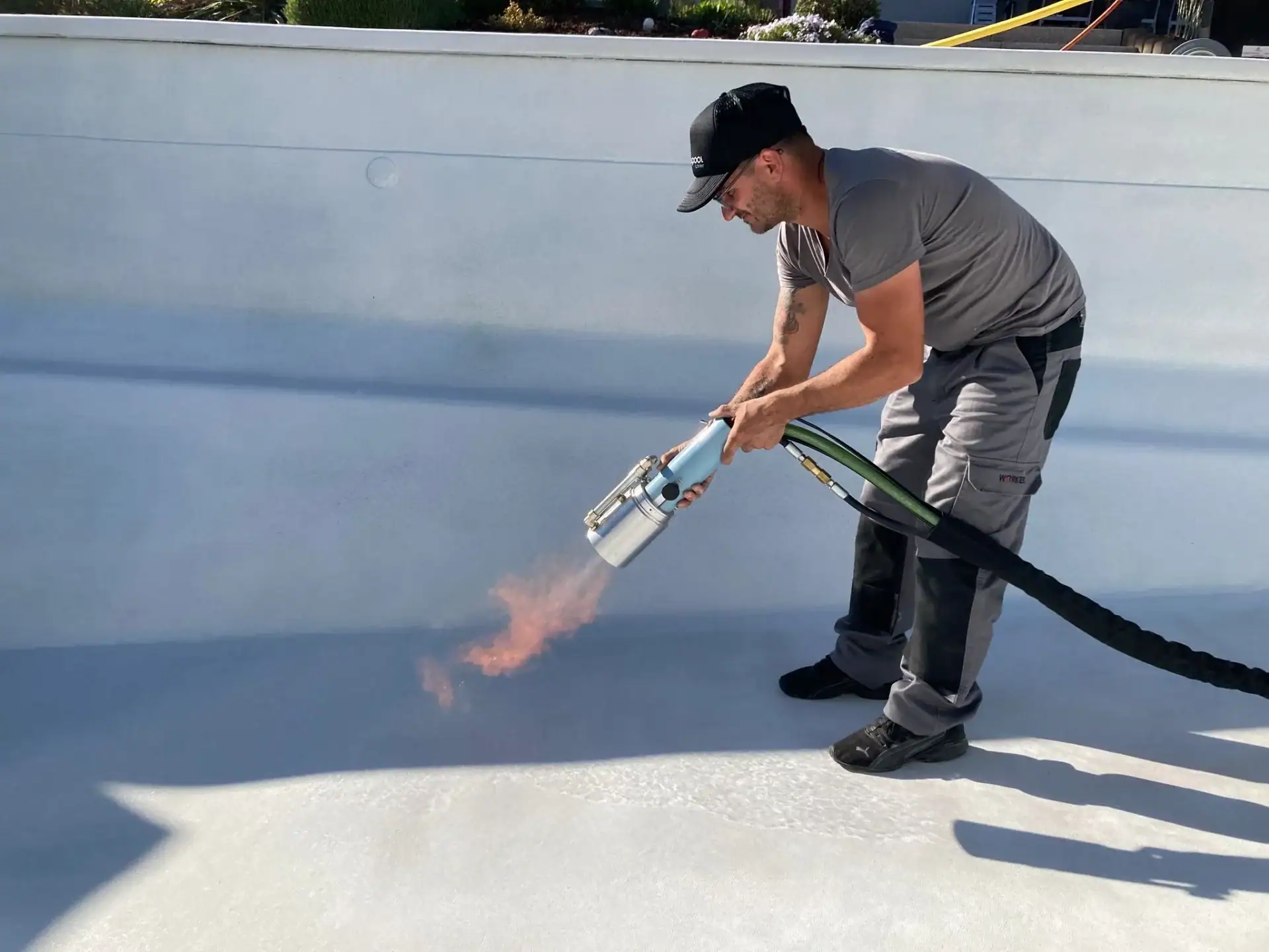 Technicien appliquant une membrane de protection dans une piscine.